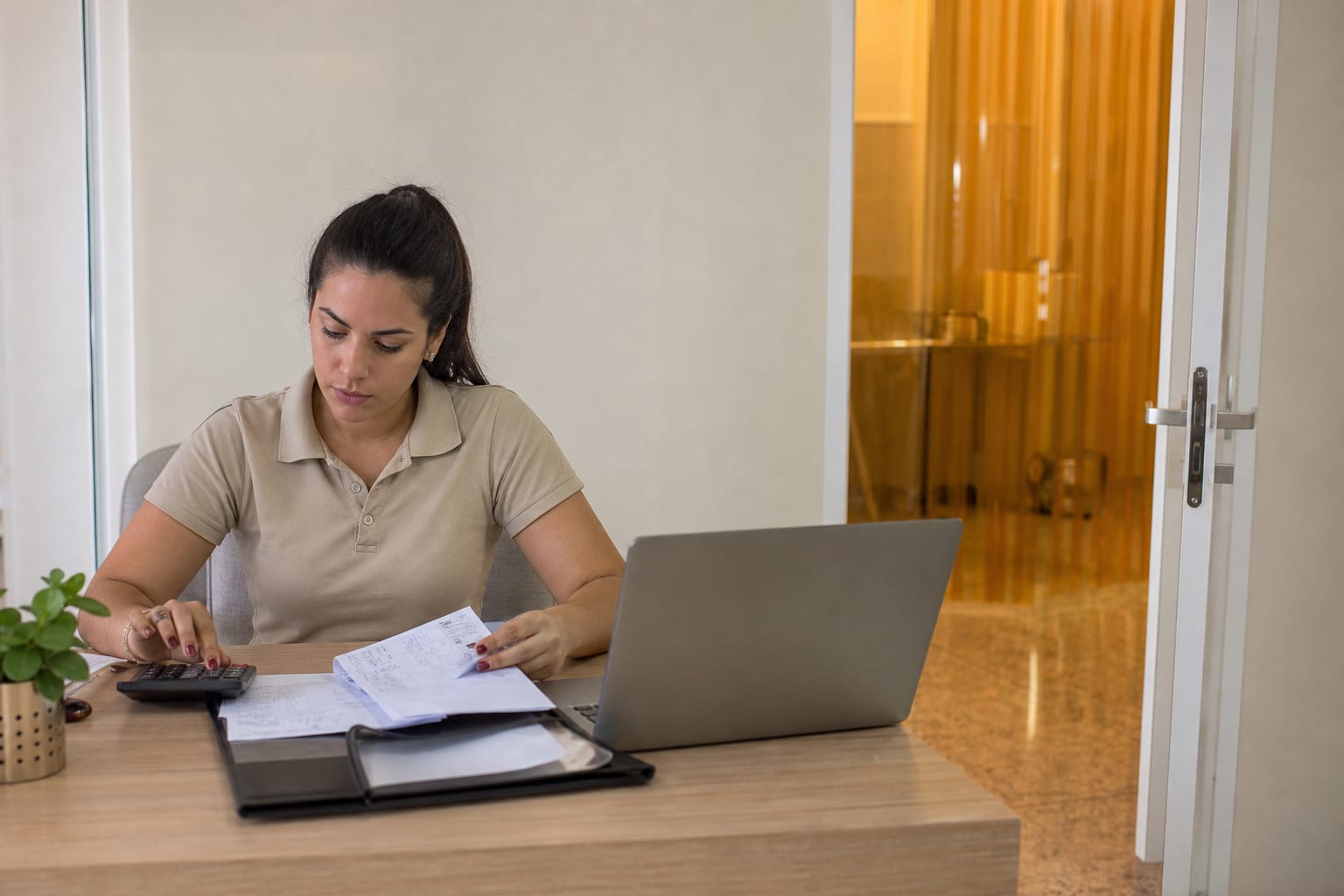 Gerente administrativa de clínica veterinária fazendo contas com notas fiscais e calculadora sobre a mesa